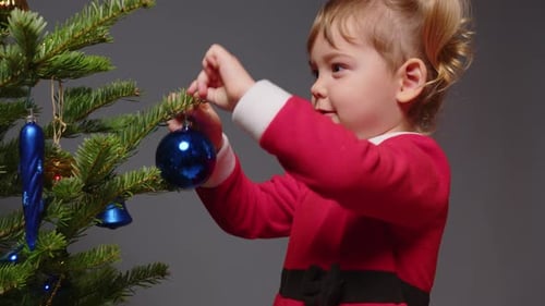 Child Decorating Christmas Tree with Blue Ornament