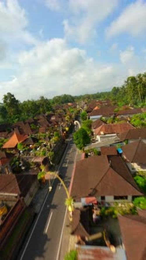 FPV Drone Shot of Motorbike Riding Through Decorated Balinese Village Indonesia