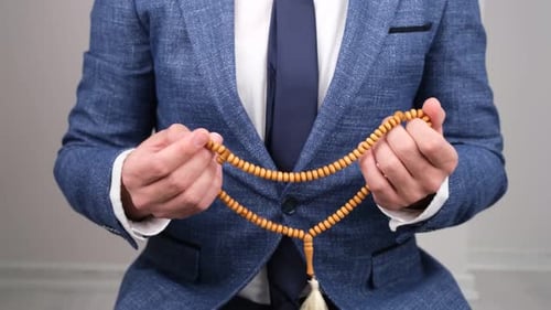 Man Counting Prayer Beads Wearing a Suit Jacket