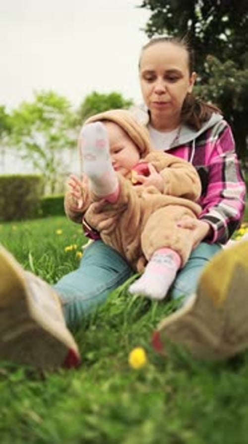 A Mother and Her Baby Enjoy a Beautiful Spring Day in the Park They are Sitting on a Blanket