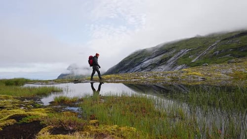 Travel Man with a Backpack Walks Along the Edge of a Cliff and Enjoys a Picturesque View of the