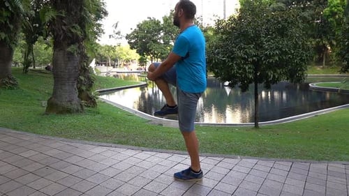 Young man stretching legs before jogging in the city park slow motion