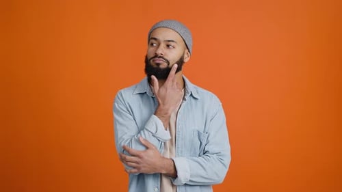 Man with Beard Pondering in Front of Orange Background