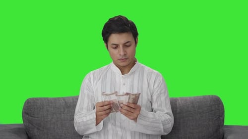 Serious Indian man counting money Green screen