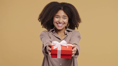 Smiling Woman Holding out Gift with Bow