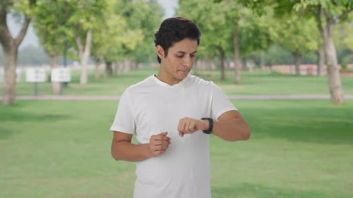 Young Adult Checks Smart Watch in Park