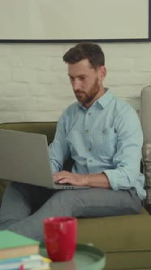 Casual Person Using Laptop in Cozy Room Informal Man with Coffee Mug Participating in Virtual