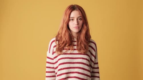 Dissatisfied girl shows thumb down in studio on yellow background