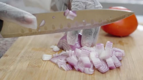 Gloved Hands Dicing Red Onion on Cutting Board