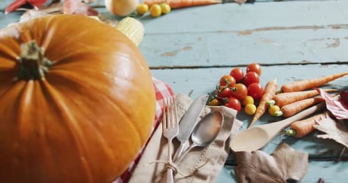 Close up view of pumpkin, multiple food ingredients and cutlery on wooden surface