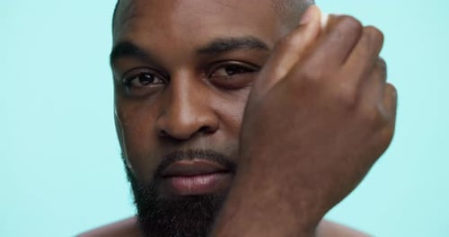 Black man, face and dropper with oil serum in studio for collagen or vitamin C on a blue background