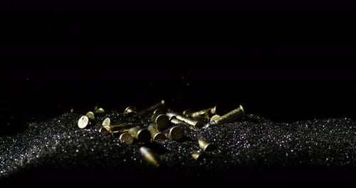 Closeup Of 22 Long Rifle Ammunition Bullets Falling On Bullet Grains In Slow Motion. studio shot