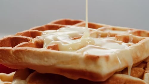 Gaufres belges saupoudrées de sucre en poudre avec lait condensé, vue de dessus sur fond blanc