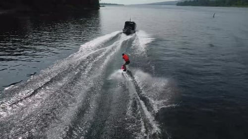 A Young Man Rides a Wakeboard A Sports Guy Rides on the Water on a Board Behind a Boat Top View From