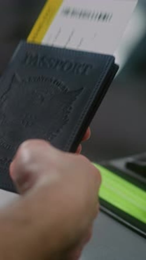 Airport Terminal Close Up of Man Sitting Holding Passport and Plane Ticket Waiting for Flight