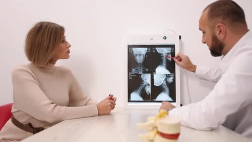 Doctor Reviews Neck X-Ray with Female Patient