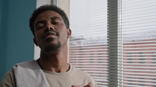 Man Sprays Cologne in Front of Window