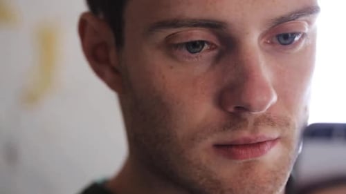 Man Looking at Phone Indoors During the Day