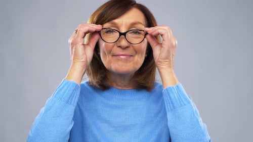 Smiling woman putting on eyeglasses in a home setting