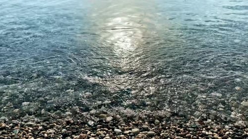 A Minimalistic Closeup Shot From the Beach to the Sea Waves with Pebbles in the Foreground