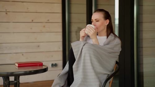 Happy Cheerful Beautiful Young Woman Enjoys Morning Coffee and a View of Nature on the Terrace of a