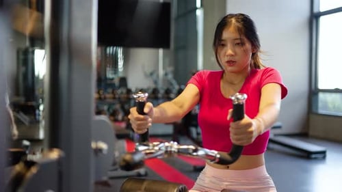 Woman Using Rowing Machine in Gym for Fitness