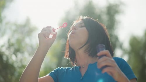 Woman Blowing Bubbles Outdoors on Sunny Day