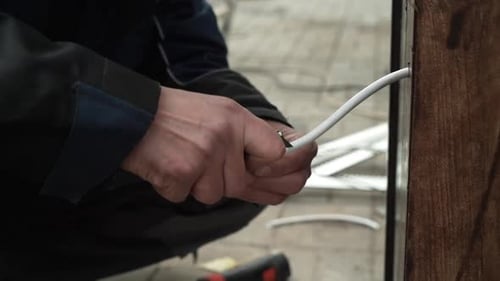 Hands Use Tool on White Electrical Cord