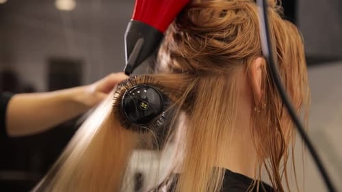 Hair Stylist Dries Long Blonde Hair With Brush