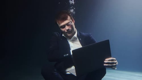 Ein Geschäftsmann in einem Anzug arbeitet unter Wasser an einem Laptop
