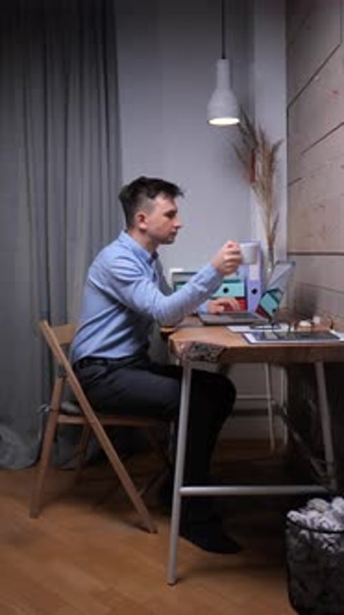 Young Man Working at Desk With Laptop and Coffee