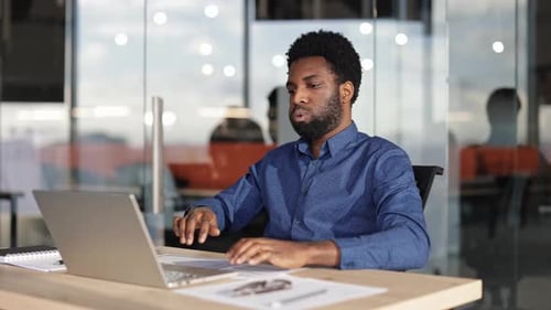 Businessman Relaxes in Office After Completing Work on Laptop
