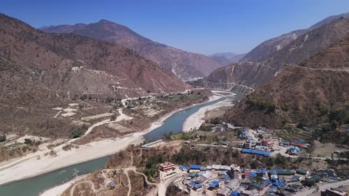 Aerial view of winding river as it gracefully carves its way through rugged mountainous terrain with