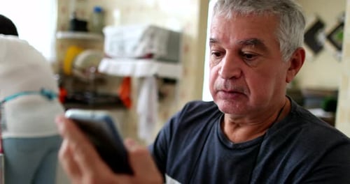 Älterer Mann benutzt Smartphone mit Lesebrille