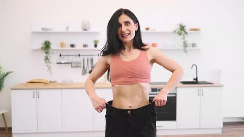 Woman Looking at Oversized Jeans on Thin Waist at Home