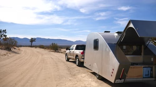 A metal teardrop travel trailer tiny house camping in the epic California desert with scenic mountai