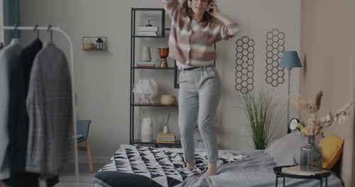 Young Woman Dancing on Bed with Headphones