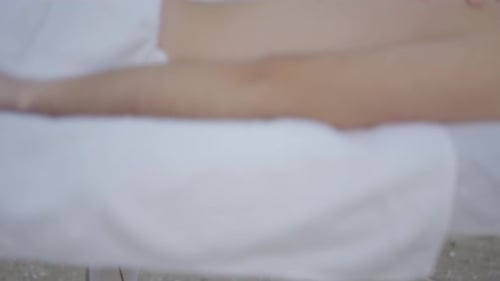 Feet and Hands of Unrecognizable Masseuse Performing Relaxing Massage at the Beach Detail Shot
