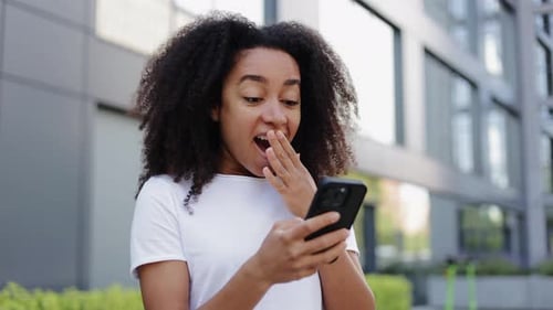 Woman Celebrates Good News on Smartphone in City
