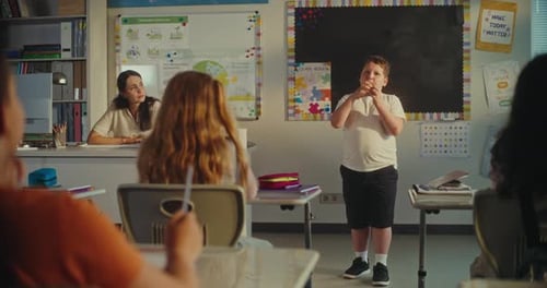 Primary School Boy Showcasing Knowledge of Ecology in Front of Class and Female Teacher