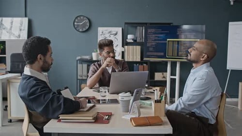 Multiethnische erwachsene IT-Kollegen diskutieren während einer Bürositzung über Softwarecode