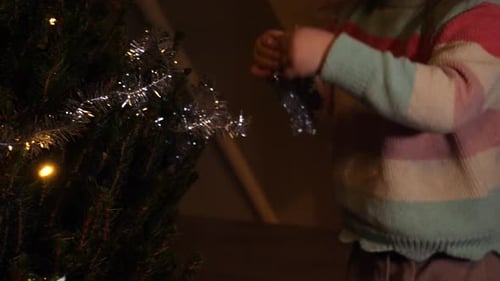 Child Decorating Christmas Tree with Silver Garland