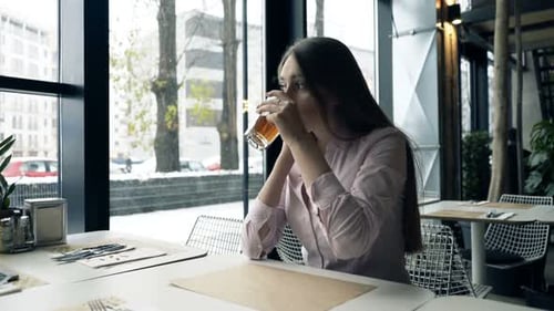 Sad, Pensive Woman Drinking Tea by the Window at Cafe Abandoned