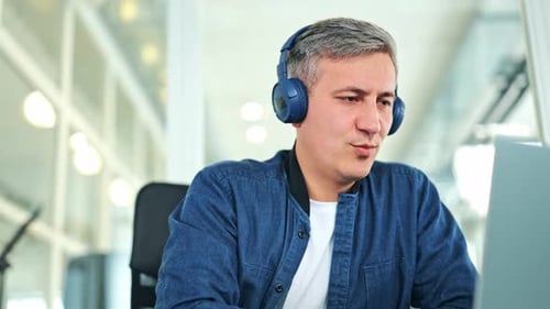 Focused Professional Man Working Online With Headphones in Office