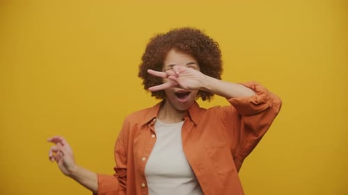 Woman Dancing Cheerfully Against a Yellow Background