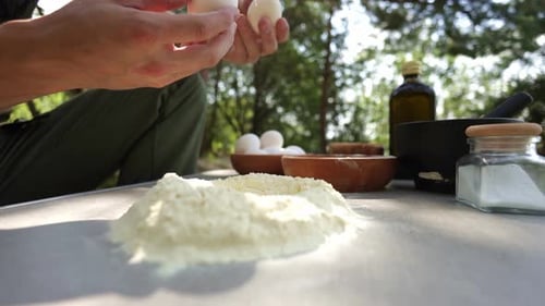 Man Cracking Eggs While Baking Outdoors