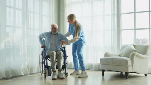 Rehabilitation Healthcare Physiotherapist Nurse Helps Old Man Patient in Wheelchair Stand Up Walking