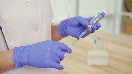 Hand Holding Syringe and Vaccine Ampoule with a Vaccine Health Care