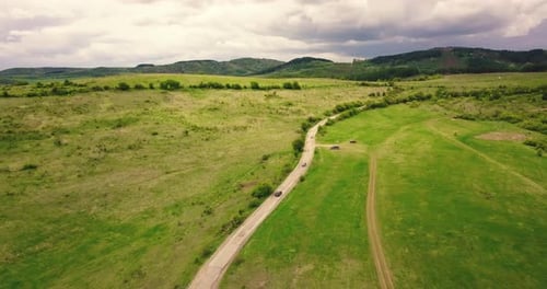 road to the mountain passing through flowering meadows from above