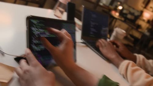 Zwei unbekannte Softwareentwickler programmieren im Büro auf Tablet und Laptop